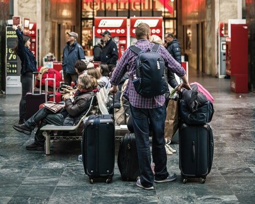 Student with a backpack and luggage at a station